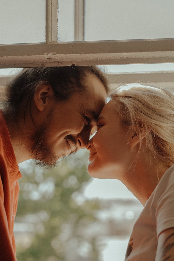 Woman in Orange Shirt Kissing Mans Cheek